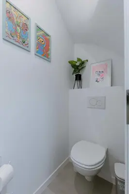 a white bathroom with a toilet and pictures on the wall at Colorful POP apartment in the heart of Antwerp in Antwerp