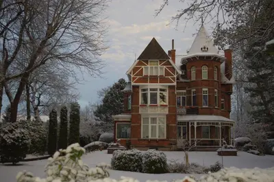 a large brick house with a turret in the snow at B&B Villa Emma in Ghent