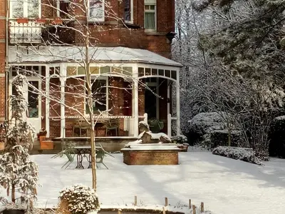 a house covered in snow with a fountain in front of it at B&B Villa Emma in Ghent