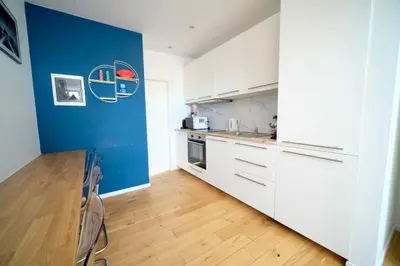 a kitchen with white cabinets and a blue wall at Easy Stay - City Center in Brussels
