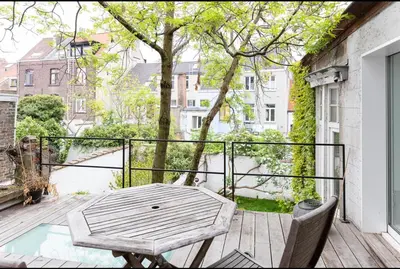 a wooden deck with a table and chairs on a balcony at Bohemian city loft in Ghent