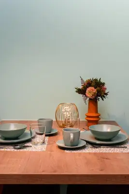 a wooden table with plates and cups and a vase at SYBA Gastenverblijf in Evergem