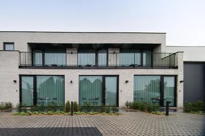 a building with large windows and a balcony at SYBA Gastenverblijf in Evergem
