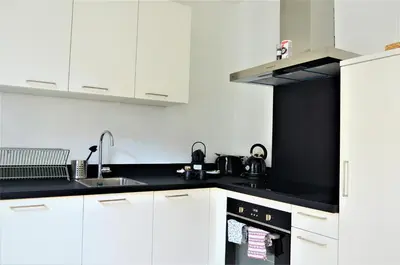 a kitchen with white cabinets and black counter tops at SLEEP INN - Palace Apartments - 2 Bedrooms in Antwerp