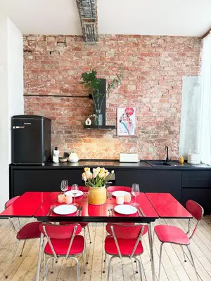 a dining room with a red table and red chairs at LouLou Home's in Antwerp