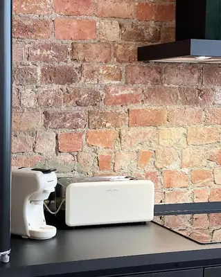 a white appliance sitting on a counter in front of a brick wall at LouLou Home's in Antwerp