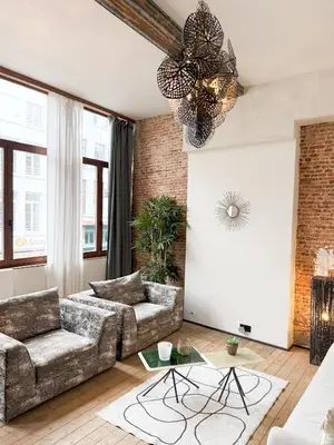 a living room with a couch and a chandelier at LouLou Home's in Antwerp