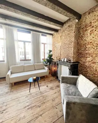a living room with a couch and a brick wall at LouLou Home's in Antwerp