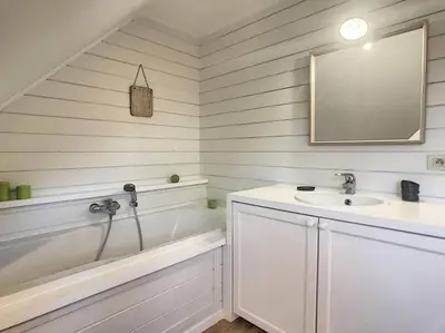 a bathroom with a tub and a sink and a mirror at Cottage en bordure bruxelloise in Wezembeek-Oppem