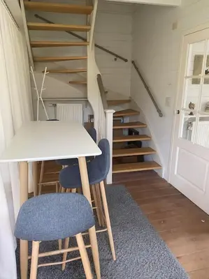 a table and chairs in a room with stairs at Cottage en bordure bruxelloise in Wezembeek-Oppem