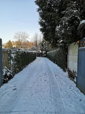 a snow covered street with a fence and a gate at Cottage en bordure bruxelloise in Wezembeek-Oppem