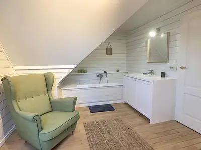 a bathroom with a sink and a chair in a room at Cottage en bordure bruxelloise in Wezembeek-Oppem