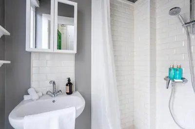 a white bathroom with a sink and a shower at SHWAY - The Handshake House in Antwerp