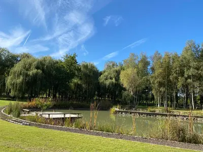a pond in a park with trees and grass at Rustiek vakantiehuis in 't groen in Lier