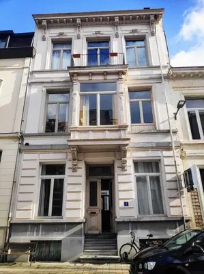 a white building with a door and a car parked in front at Gezellig gerenoveerd herenhuis in het centrum in Antwerp