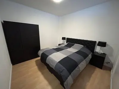 a bedroom with a black and white bed and two lamps at Appartement Brussels Expo Atomium in Grimbergen