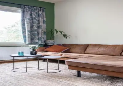 a living room with a brown couch and two tables at Cozy 3BR Home near Meir in Antwerp City Centre in Antwerp