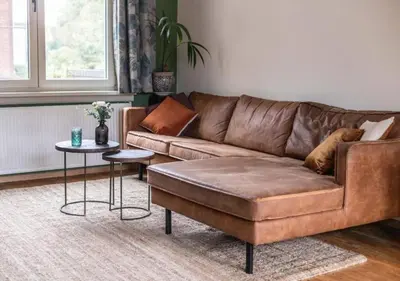 a living room with a brown couch and a table at Cozy 3BR Home near Meir in Antwerp City Centre in Antwerp