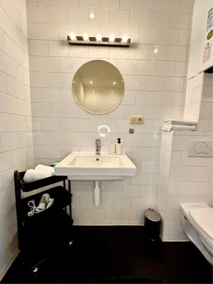 a white bathroom with a sink and a mirror at Luxury Suites Museum by Rikas Hotels in Antwerp
