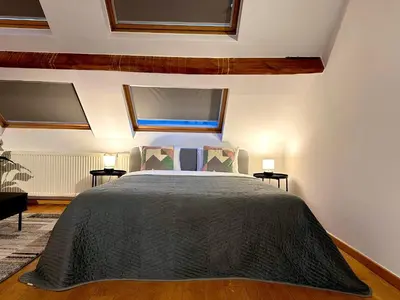 a bedroom with a large bed with two windows at Luxury Suites Museum by Rikas Hotels in Antwerp