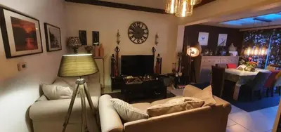 a living room with a couch and a clock on the wall at COSY HOUSE 6BEDROOMS GARDEN in Mortsel