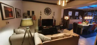 a living room with a couch and a clock on the wall at COSY HOUSE 6BEDROOMS GARDEN in Mortsel