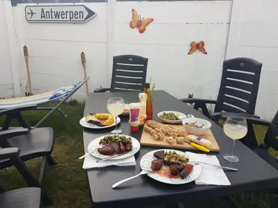 a table with plates of food and glasses of wine at COSY HOUSE 6BEDROOMS GARDEN in Mortsel