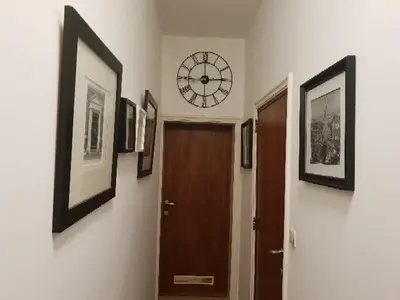 a hallway with a clock on the wall and a door at COSY HOUSE 6BEDROOMS GARDEN in Mortsel