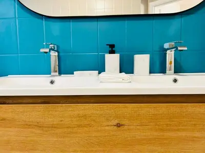 a bathroom with a white sink and a blue wall at Appart Brussels EXPO & ATOMIUM in Grimbergen