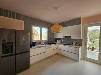 a kitchen with white cabinets and a black refrigerator at BNB Green refuge: Vakantiehuis met zeer grote tuin in Londerzeel