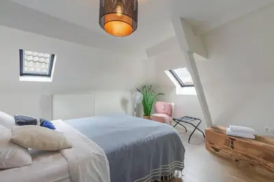 a white bedroom with a bed and a chair at Cosy duplex nearby city centre of Ghent for 6 in Ghent