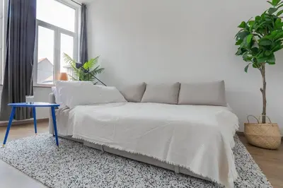 a bed in a white room with a blue table at Ruime studio in centrum voor 4 in Ghent