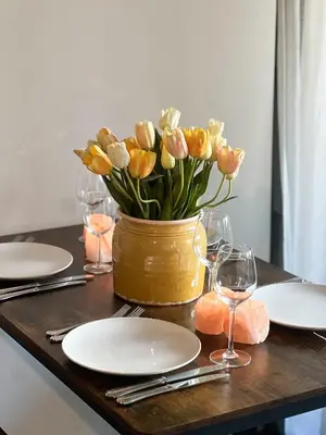 a vase of flowers on a table with plates and glasses at Sān home’s in Antwerp