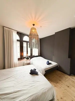 a bedroom with two beds and a chandelier at Sān home’s in Antwerp