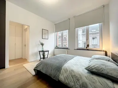 a bedroom with a large bed and a window at Elegant Flat Cinquantenaire in Brussels