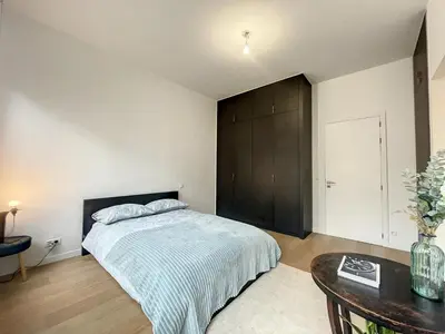 a bedroom with a large bed and a table at Elegant Flat Cinquantenaire in Brussels