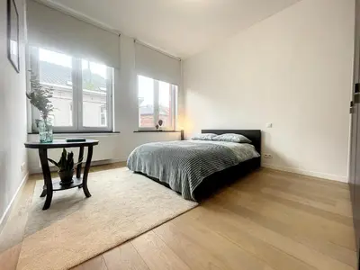 a bedroom with a bed and a table in it at Elegant Flat Cinquantenaire in Brussels