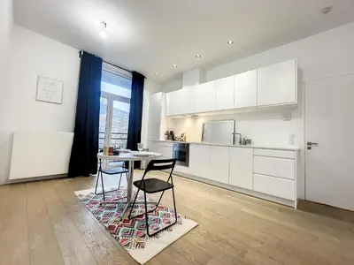 a kitchen with white cabinets and a table and chairs at Elegant Flat Cinquantenaire in Brussels