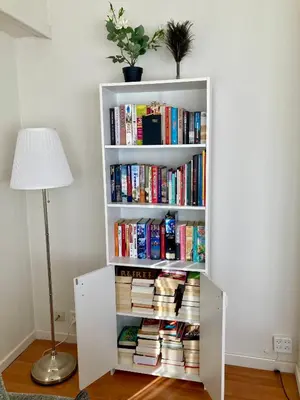 a white book shelf filled with books next to a lamp at Charming Sunny 100m2 Entire Apartment with 2 bedrooms in Brasschaat