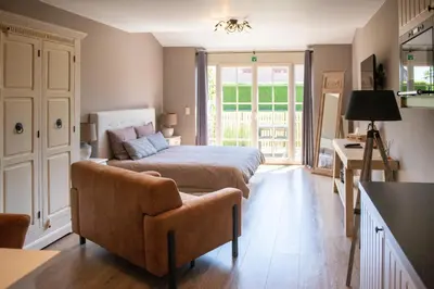 a bedroom with a bed and a couch and a table at B&B Fragaria in Hoogstraten