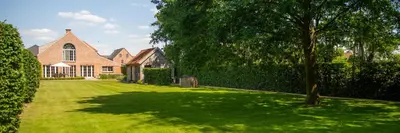 a large house with a tree in the yard at B&B Fragaria in Hoogstraten