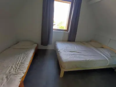 two beds in a small room with a window at Huis Belijn in Lokeren