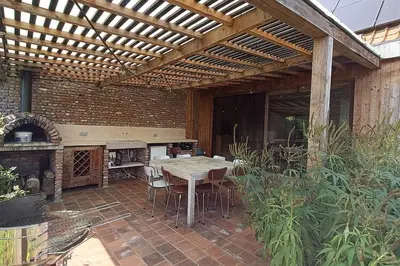 a patio with a wooden pergola with a table and chairs at Huis Belijn in Lokeren