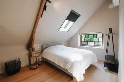 a bedroom with a white bed and a window at Schuur 80 in Haasdonk