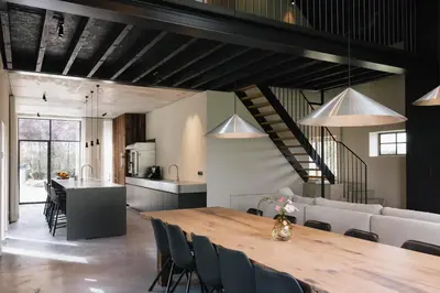a dining room and kitchen with a wooden table and chairs at Schuur 80 in Haasdonk