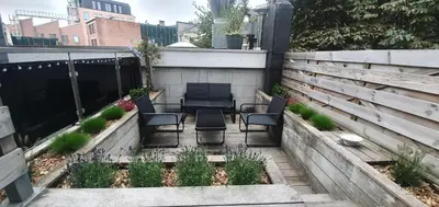 a backyard patio with chairs and a fence at The South Suite - trendy duplex op het Zuid in Antwerp