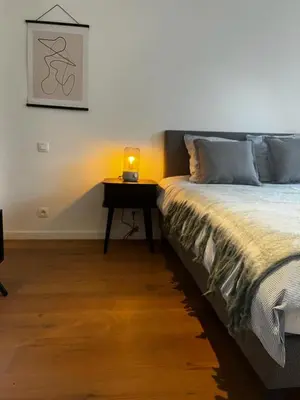 a bedroom with a bed and a table with a lamp at The South Suite - trendy duplex op het Zuid in Antwerp