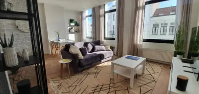 a living room with a couch and a table at The South Suite - trendy duplex op het Zuid in Antwerp