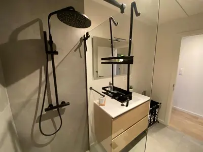 a bathroom with a shower with a sink and a mirror at Luxury & cozy apartment in Lubbeek