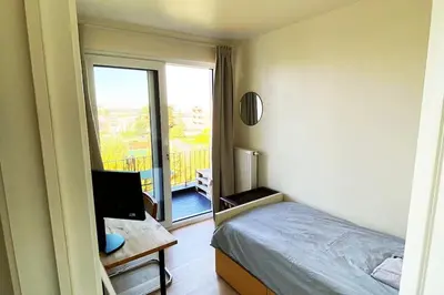 a bedroom with a bed and a desk and a window at Classy flat with awesome view and great location! in Antwerp